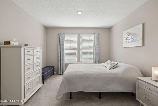 bedroom featuring light carpet and a textured ceiling