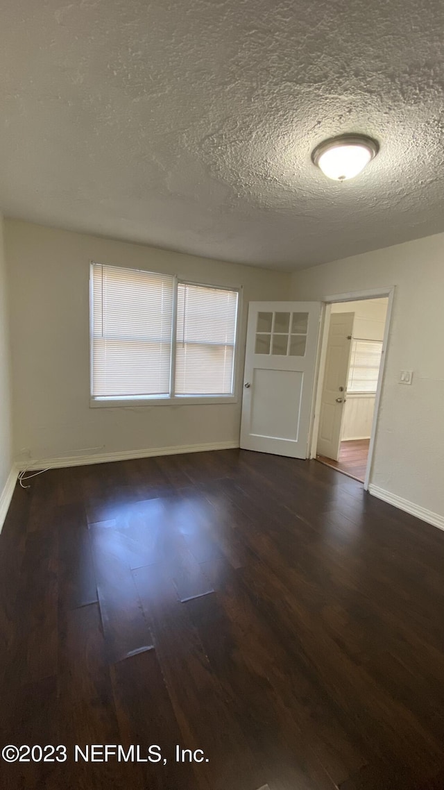 spare room with a textured ceiling and dark hardwood / wood-style floors