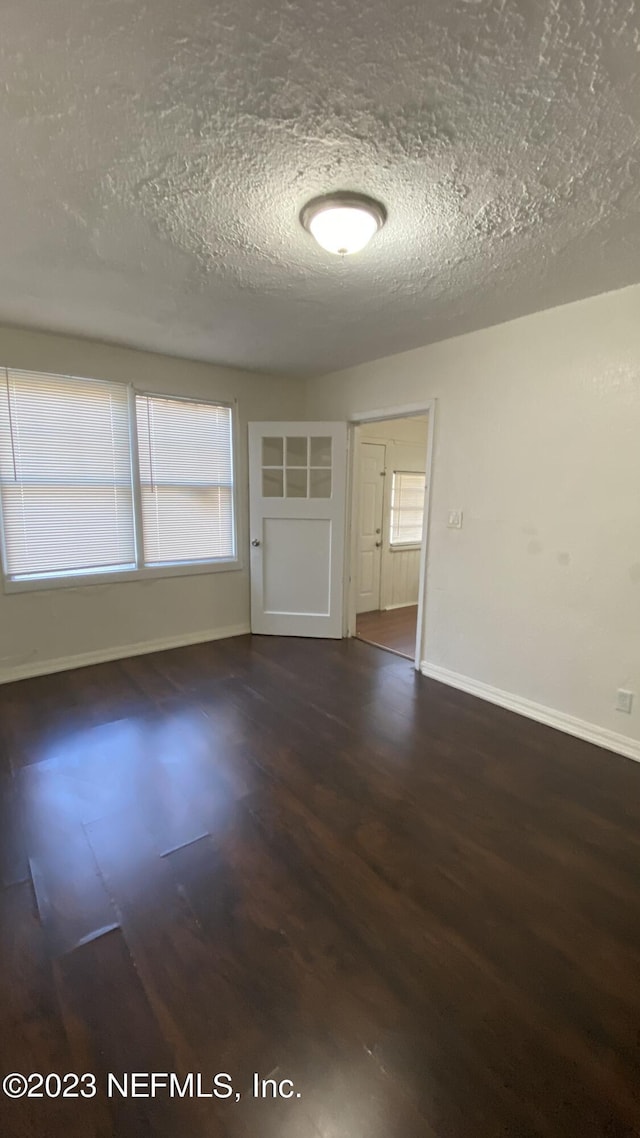 unfurnished room featuring dark hardwood / wood-style floors and a textured ceiling