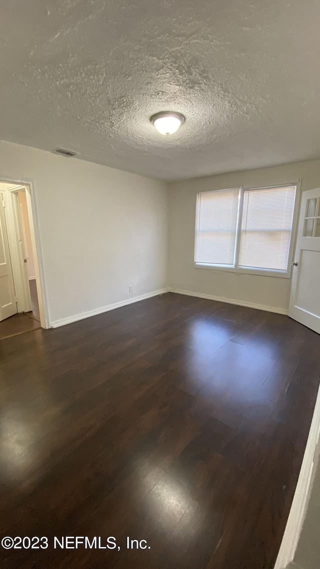 unfurnished room featuring dark hardwood / wood-style flooring and a textured ceiling