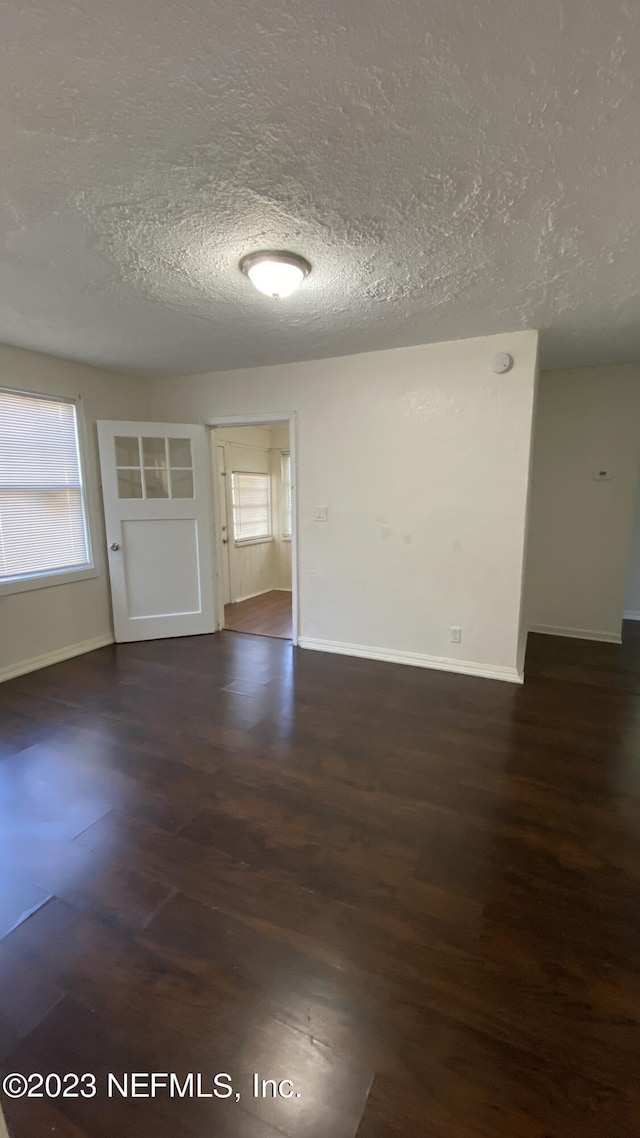 spare room featuring dark hardwood / wood-style flooring and a textured ceiling