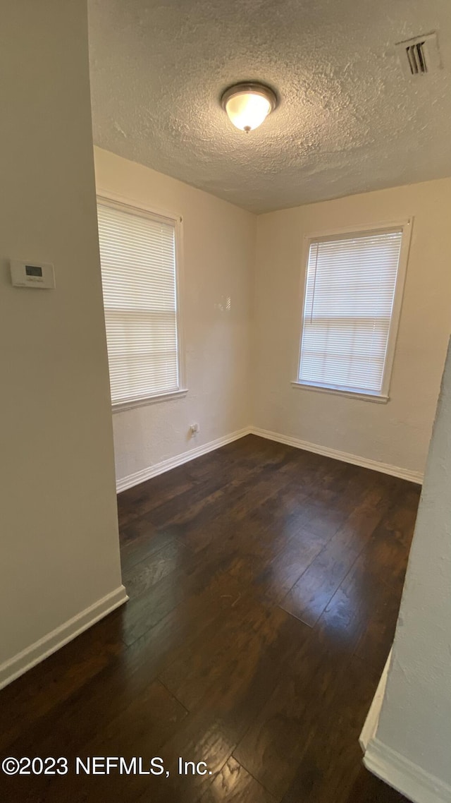 unfurnished room featuring a textured ceiling and dark hardwood / wood-style flooring