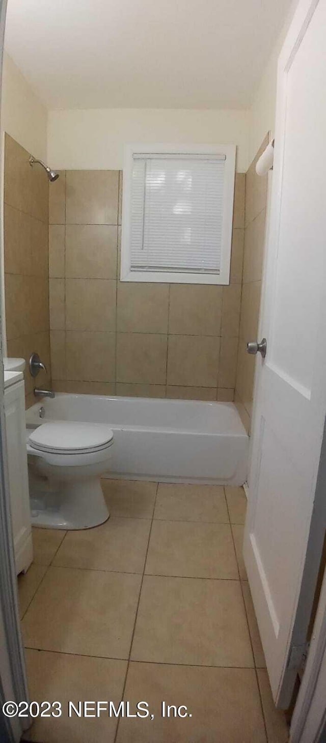 bathroom with tile patterned flooring, toilet, and tiled shower / bath