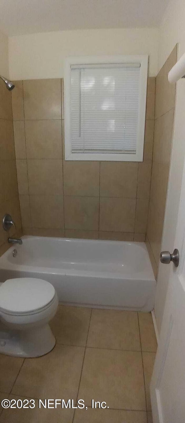 bathroom with tile patterned floors, tiled shower / bath combo, and toilet