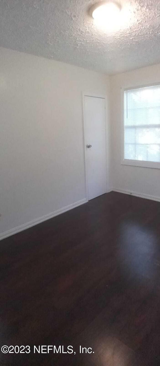 unfurnished room featuring dark hardwood / wood-style floors and a textured ceiling