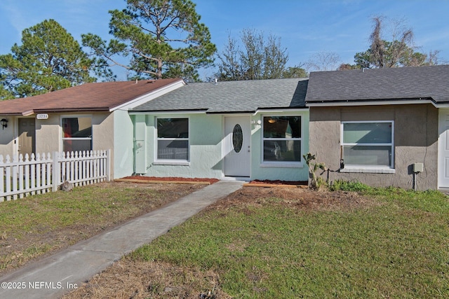 single story home featuring roof with shingles, a front yard, fence, and stucco siding