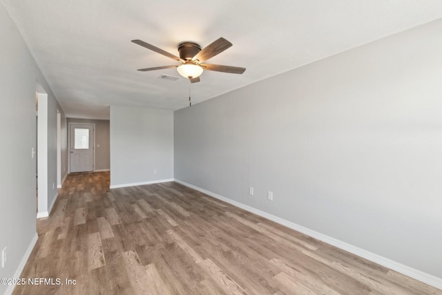 spare room featuring visible vents, wood finished floors, a ceiling fan, and baseboards