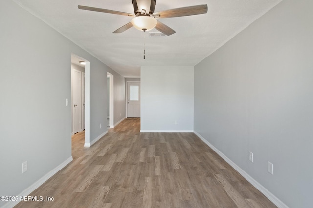 empty room with light wood-type flooring, visible vents, baseboards, and a ceiling fan