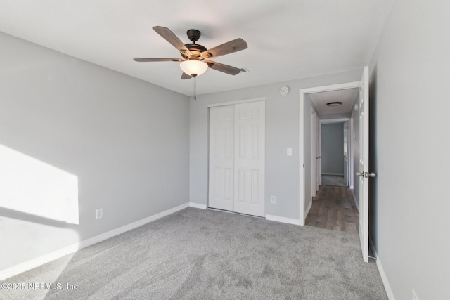 unfurnished bedroom featuring carpet, a closet, ceiling fan, and baseboards