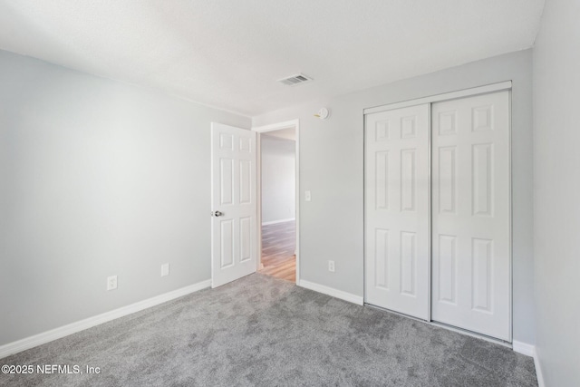 unfurnished bedroom featuring baseboards, a closet, visible vents, and carpet flooring