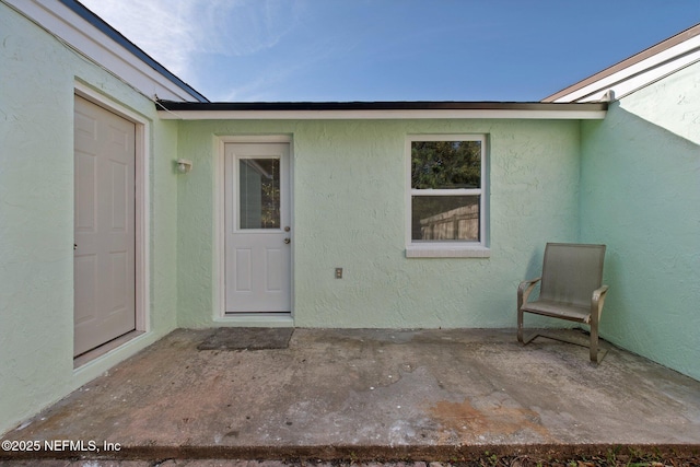 doorway to property featuring a patio area and stucco siding