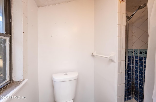 bathroom with toilet and a tile shower