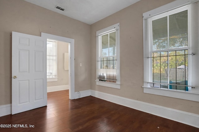 empty room with dark wood-type flooring and a healthy amount of sunlight