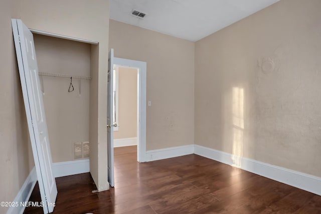 unfurnished bedroom with dark wood-type flooring and a closet