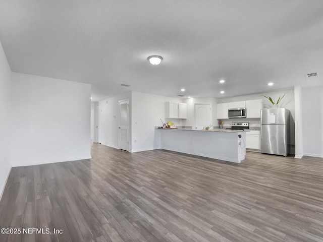 kitchen featuring kitchen peninsula, appliances with stainless steel finishes, light hardwood / wood-style floors, and white cabinetry