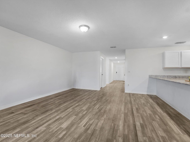 unfurnished living room featuring light wood-type flooring and a textured ceiling