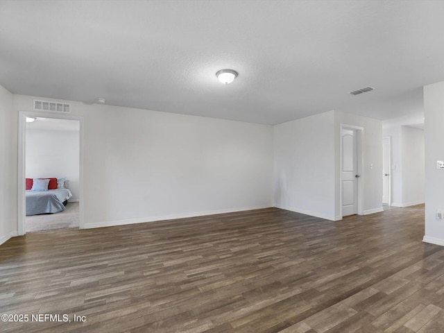 unfurnished room with a textured ceiling and dark wood-type flooring