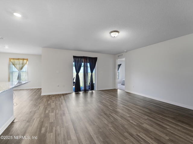 unfurnished room featuring dark hardwood / wood-style flooring, a healthy amount of sunlight, and a textured ceiling