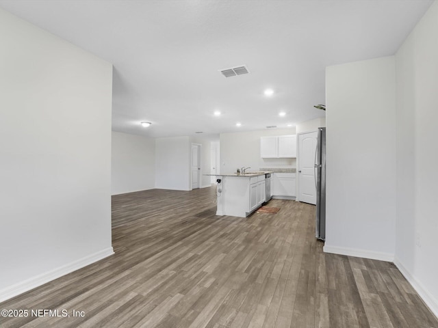 kitchen with a center island with sink, sink, hardwood / wood-style flooring, white cabinetry, and stainless steel appliances