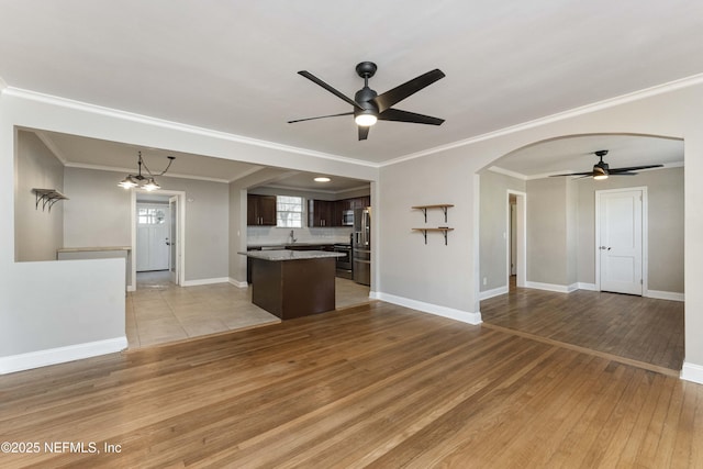 kitchen with a center island, ornamental molding, light hardwood / wood-style floors, ceiling fan with notable chandelier, and dark brown cabinetry