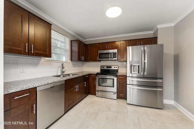 kitchen with appliances with stainless steel finishes, light stone countertops, ornamental molding, decorative backsplash, and sink