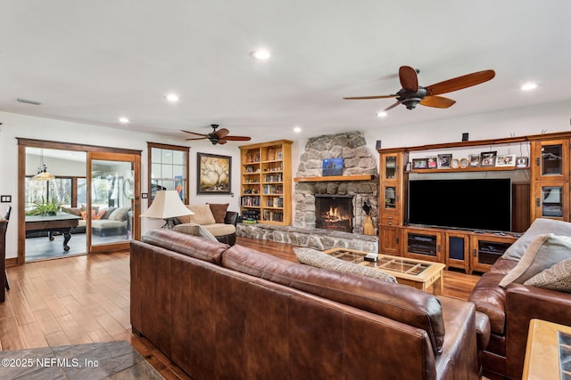 living room featuring ceiling fan and a stone fireplace