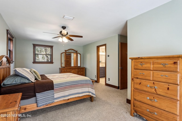 bedroom with ceiling fan, light colored carpet, and ensuite bath