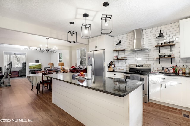 kitchen with decorative backsplash, wall chimney exhaust hood, stainless steel appliances, white cabinets, and a kitchen island