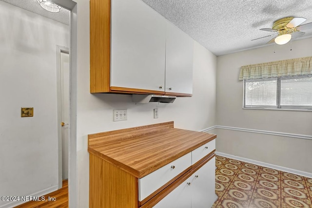 kitchen featuring ceiling fan, white cabinets, and a textured ceiling