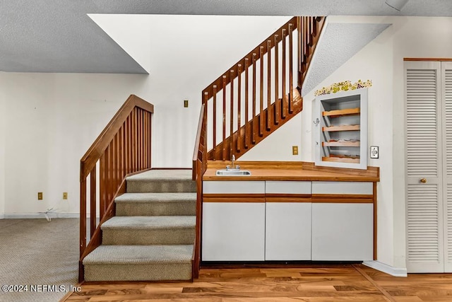 stairs with sink and a textured ceiling