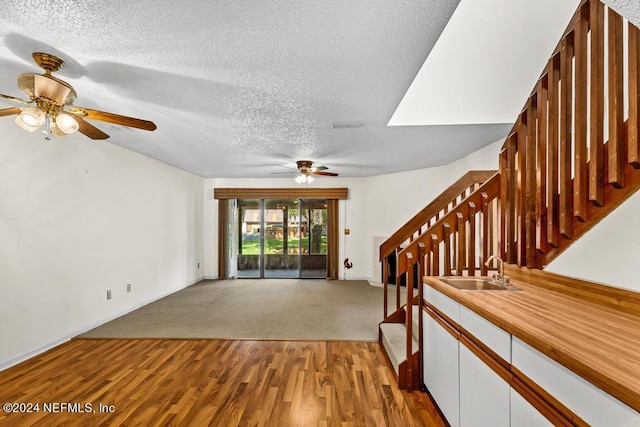 interior space with a textured ceiling, ceiling fan, light hardwood / wood-style floors, and sink