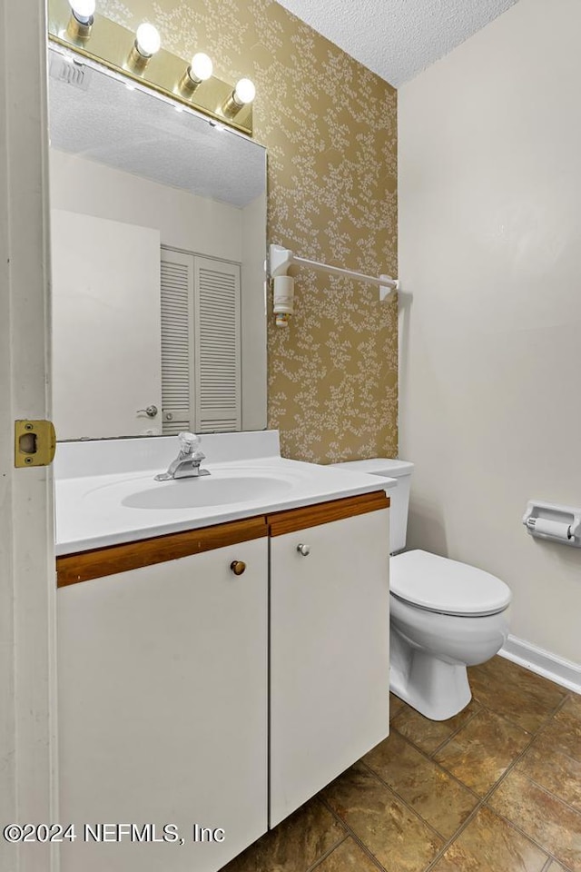 bathroom with vanity, a textured ceiling, and toilet