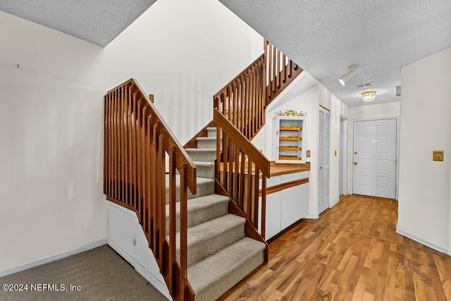 stairs with hardwood / wood-style floors and a textured ceiling