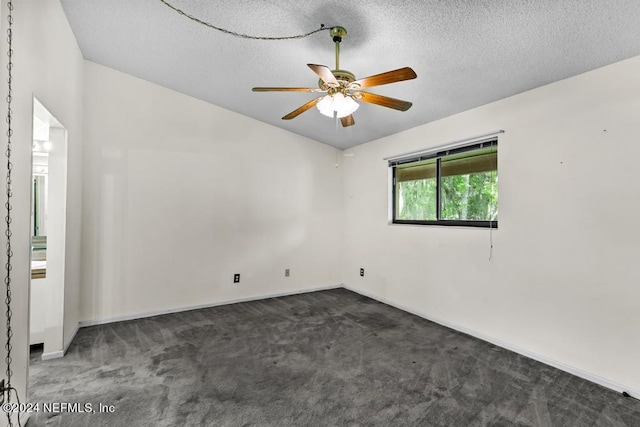 spare room with dark colored carpet, ceiling fan, and a textured ceiling