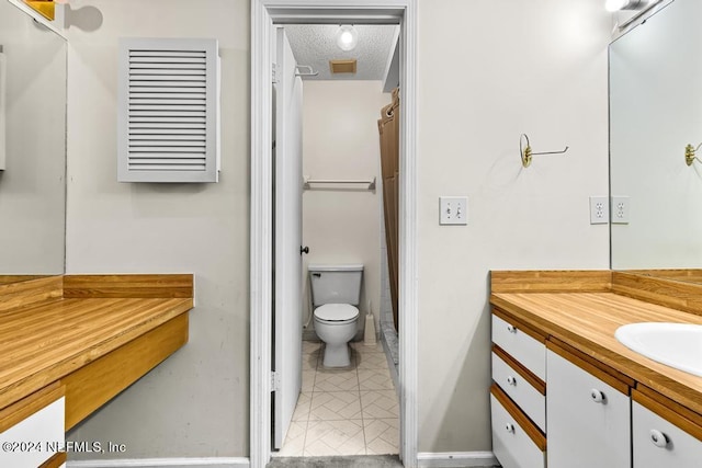 bathroom featuring vanity, a textured ceiling, and toilet