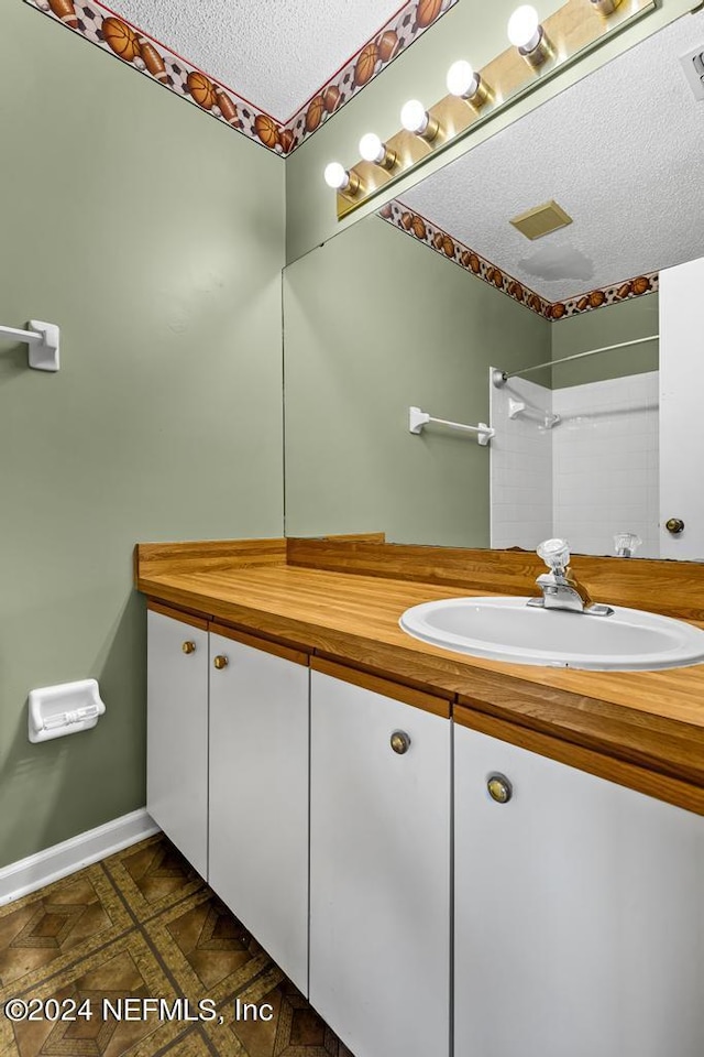 bathroom featuring tile patterned floors, vanity, a textured ceiling, and walk in shower