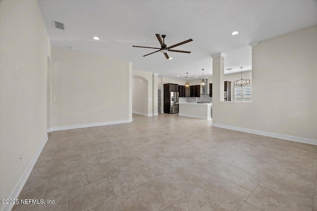 unfurnished living room featuring ceiling fan with notable chandelier