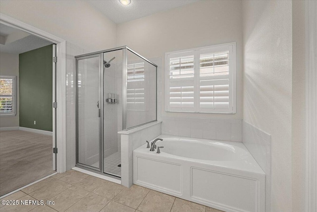 bathroom featuring tile patterned flooring, shower with separate bathtub, and a textured ceiling