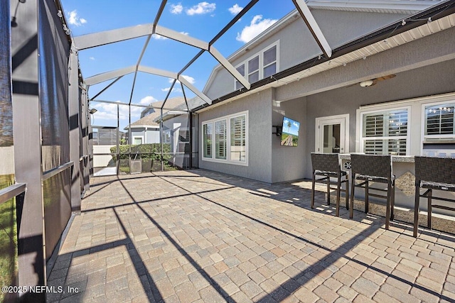 view of patio / terrace featuring glass enclosure and exterior bar