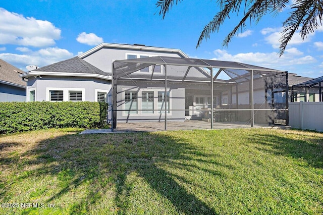 back of house with a patio, glass enclosure, and a lawn