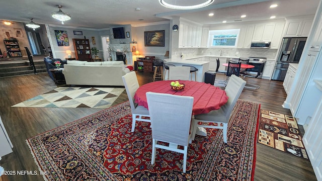 dining space with recessed lighting, dark wood finished floors, a fireplace, and crown molding