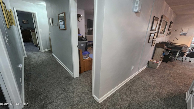 hallway featuring carpet and baseboards