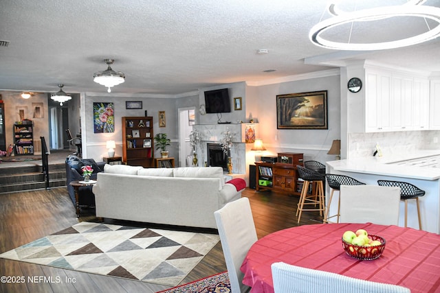 living room featuring a fireplace, a textured ceiling, dark wood-type flooring, and crown molding