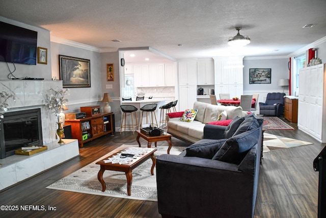 living room with a textured ceiling, ornamental molding, a fireplace, and dark wood-type flooring