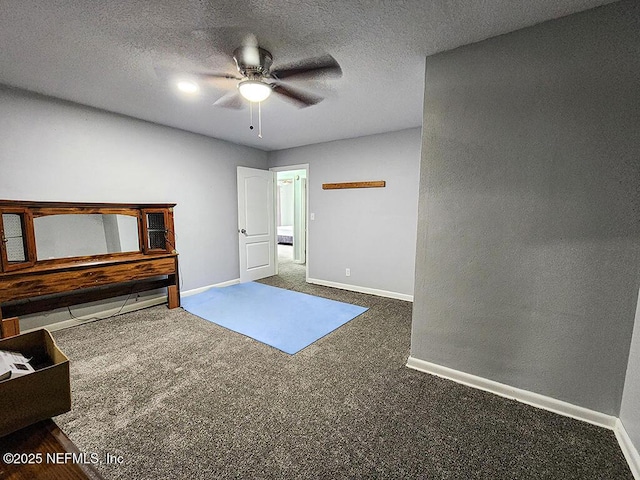 interior space with baseboards, a textured ceiling, carpet floors, and a ceiling fan