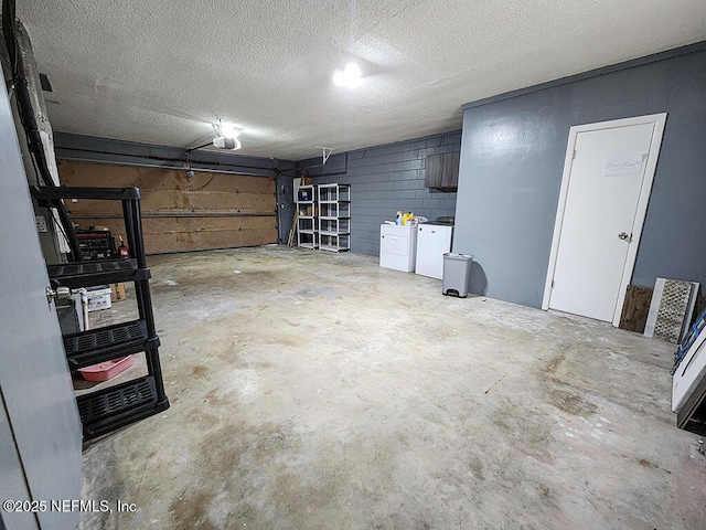 garage with independent washer and dryer, a garage door opener, and concrete block wall