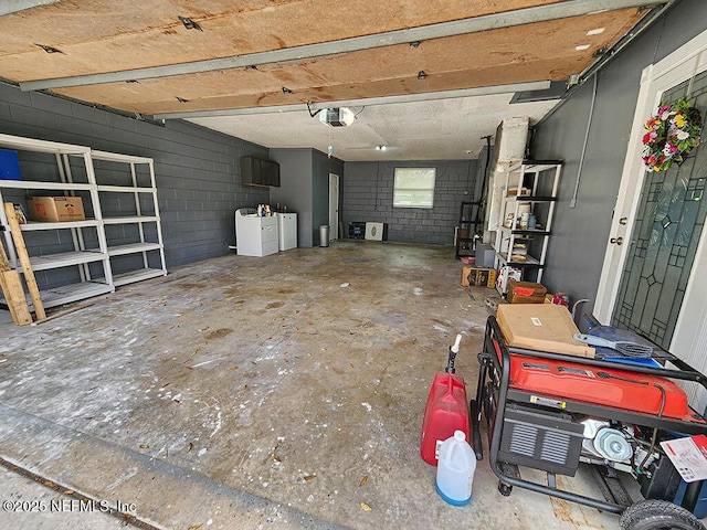 garage featuring a garage door opener, concrete block wall, and washer and clothes dryer