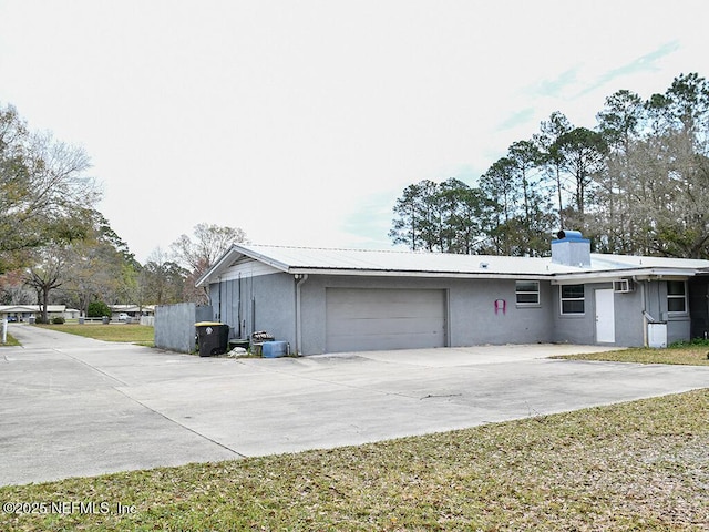 exterior space featuring driveway, a chimney, stucco siding, a garage, and metal roof