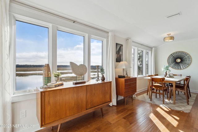 interior space with a wealth of natural light, a water view, and dark wood-type flooring