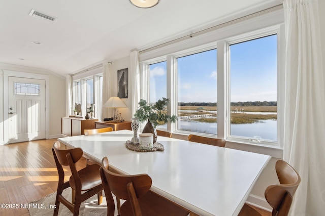 dining area with a water view and hardwood / wood-style flooring